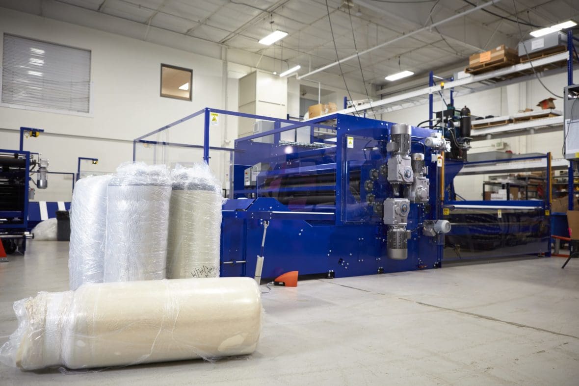 Rolled packages in front of CF1396 mattress compression machine